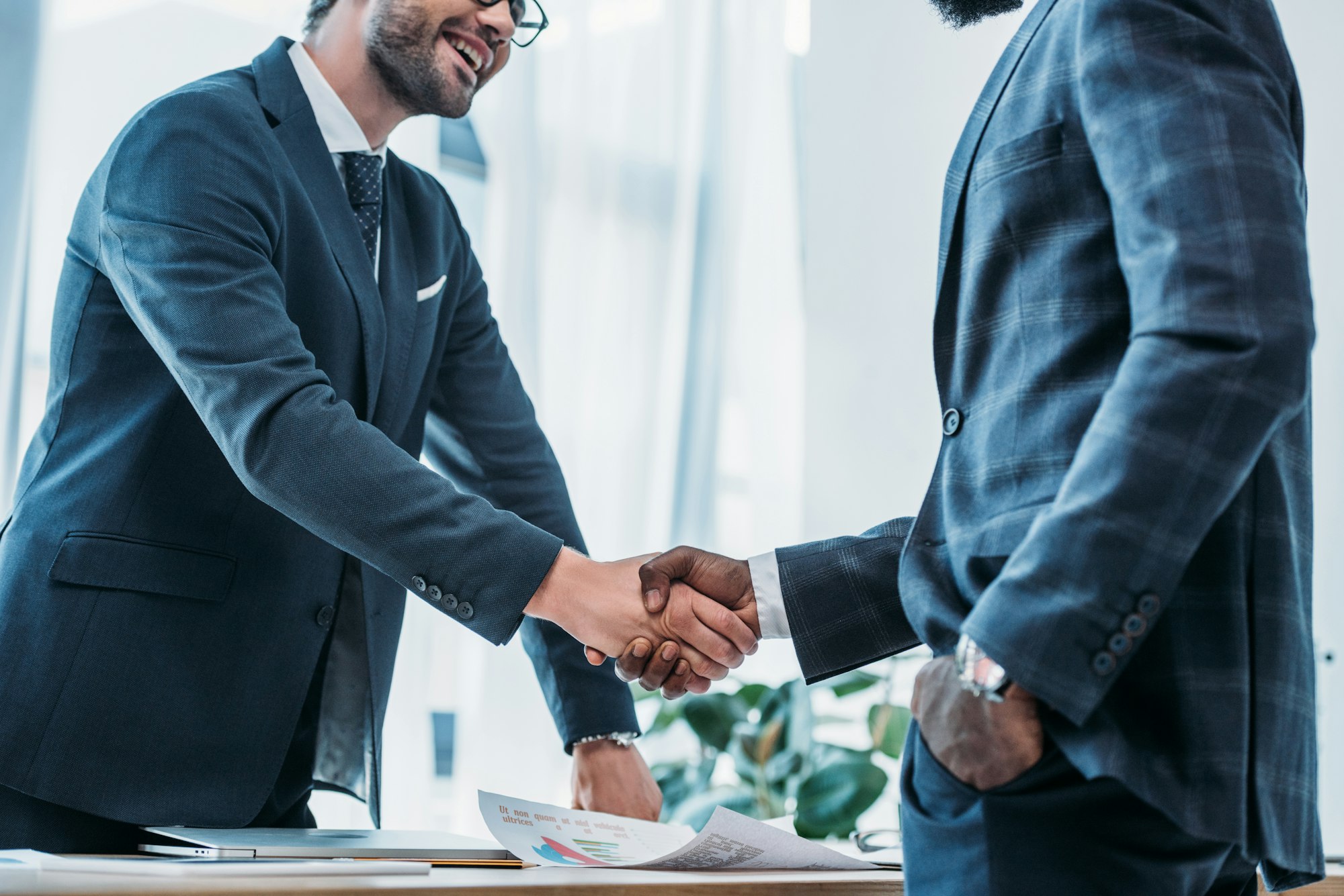 cropped image of smiling multicultural businessmen shaking hands in office