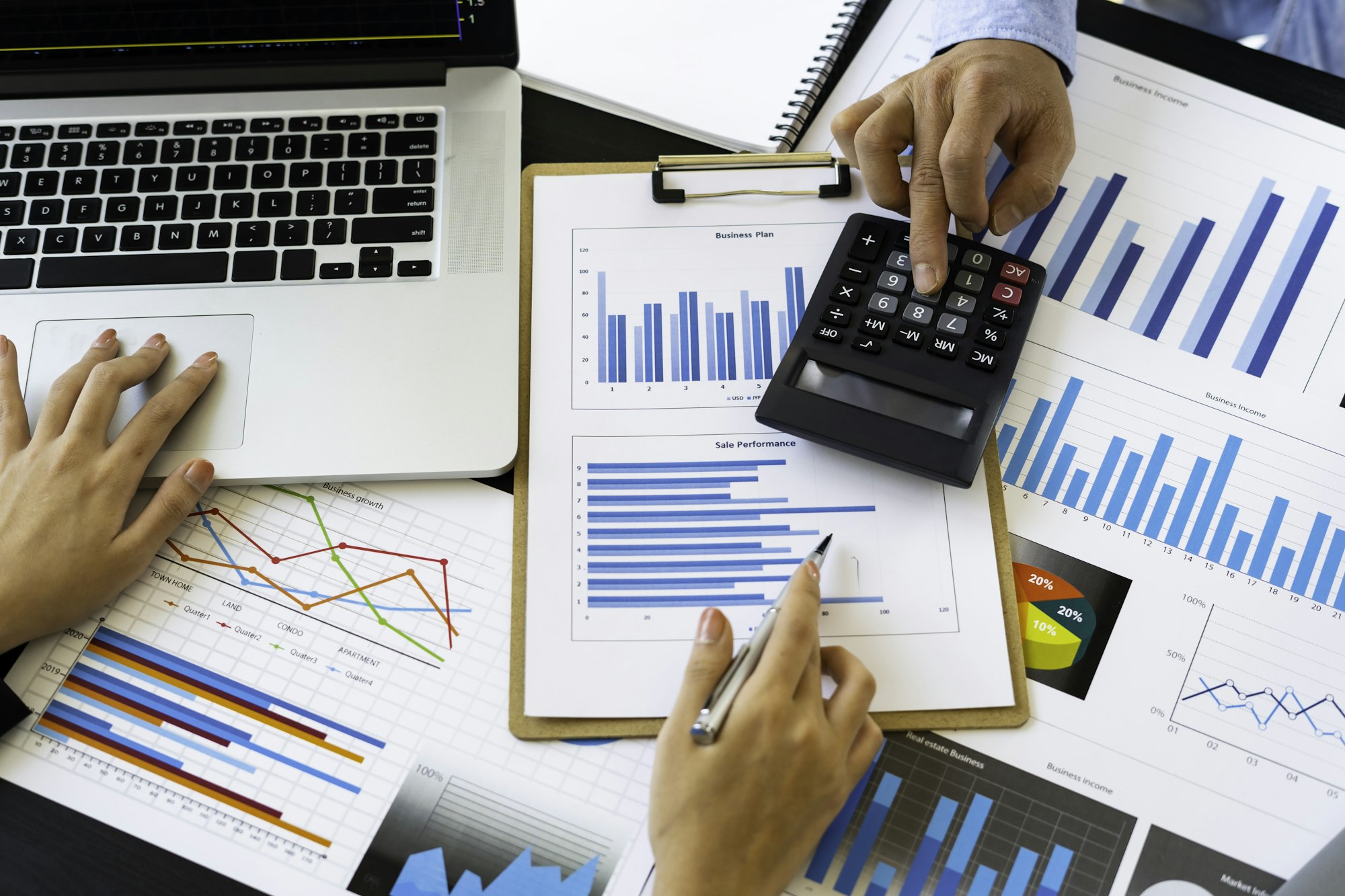 Top view of Finance business people or accountants point to the graph and use a calculator to calcul